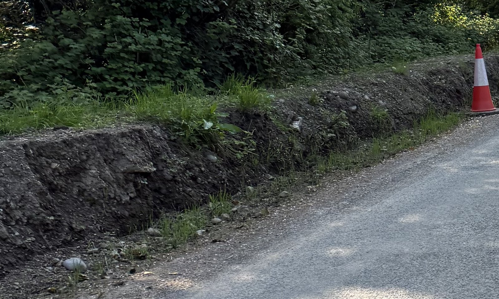 A detail of exposed earth and loose material beside the surfaced road