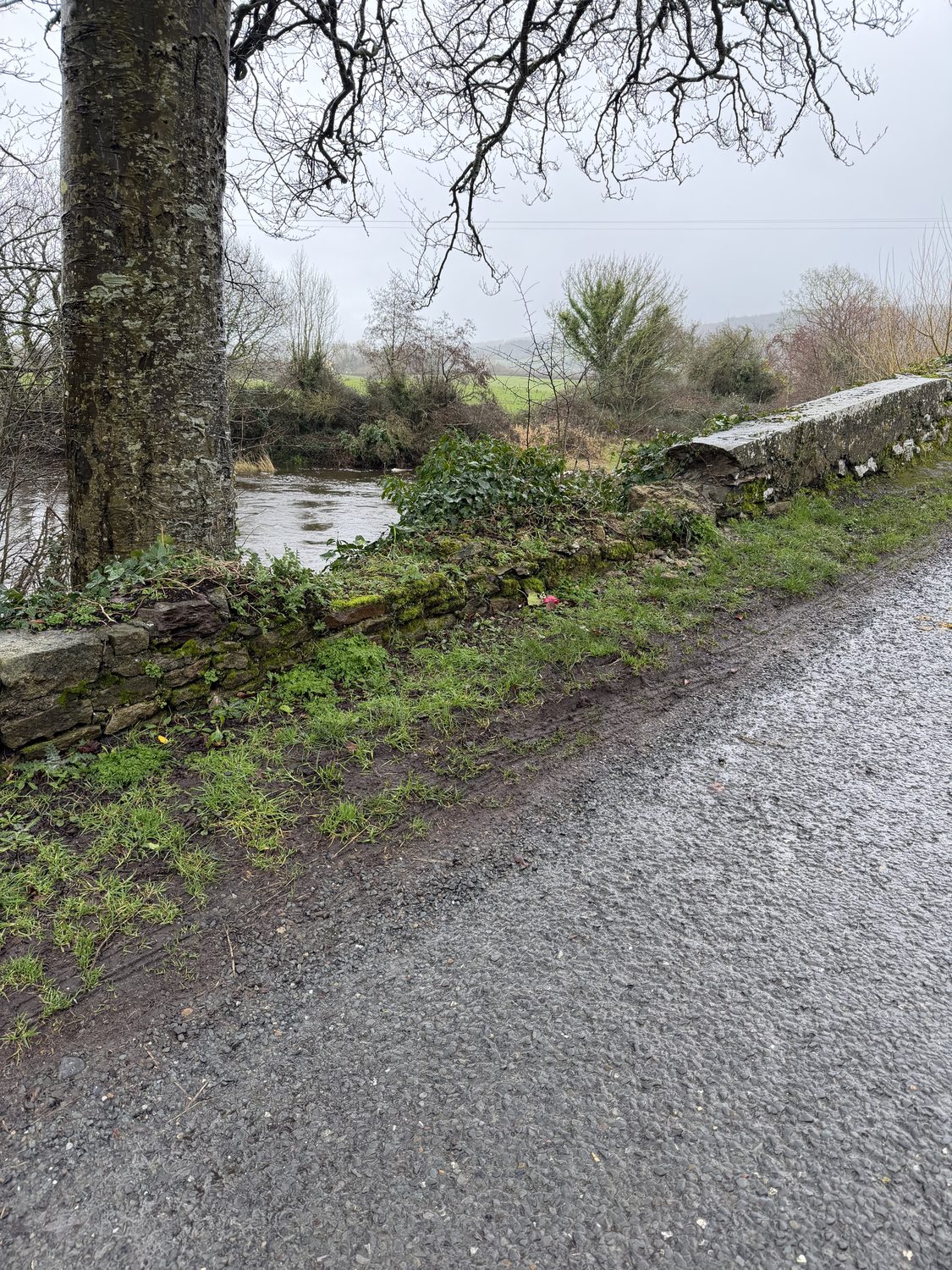 A low damaged section of bridge parapet with the river beyond