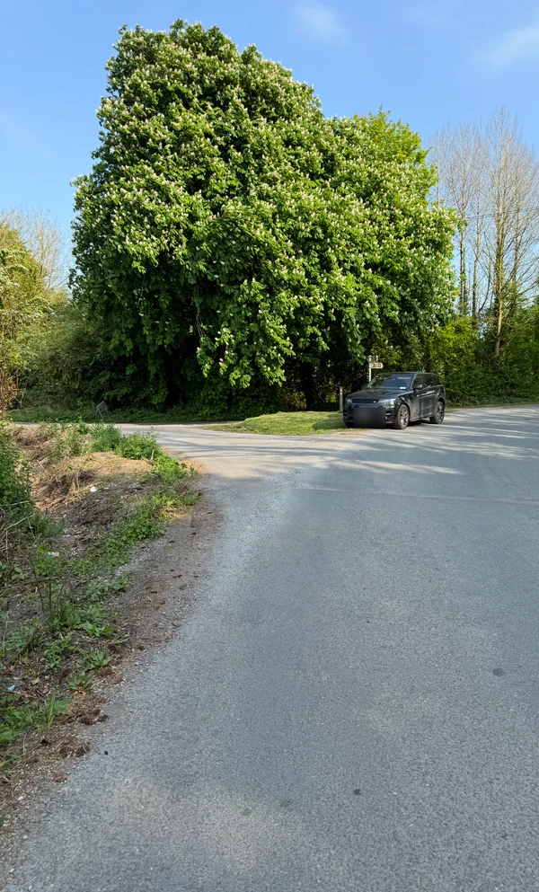 Wider view of the roadside channel and bend. Black screenshot bars removed; vehicle registration obscured for privacy.